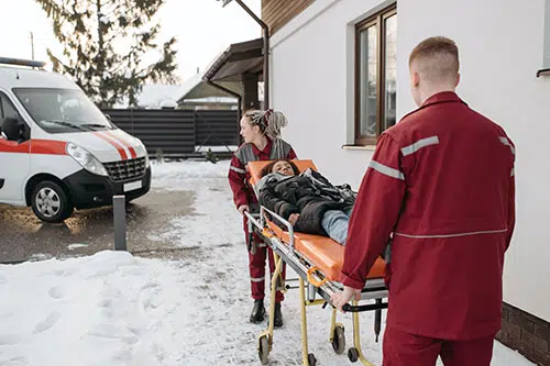 "Ein Auto mit Winterreifen auf schneebedeckter Straße vor einem Gebäude."